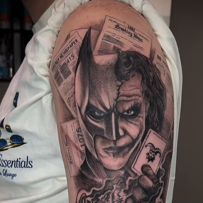 Black and grey split-face portrait tattoo with newspaper clipping background, by Thelmo